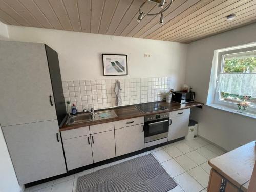 a kitchen with white cabinets and a sink and a window at Oxtown City Apartment in Ochsenhausen