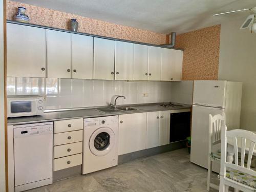 kuchnia z białymi szafkami, zlewem i zmywarką do naczyń w obiekcie Apartamento jardines tropicales dos piscinas vera playa las marinas urbanización vera coast w mieście Vera