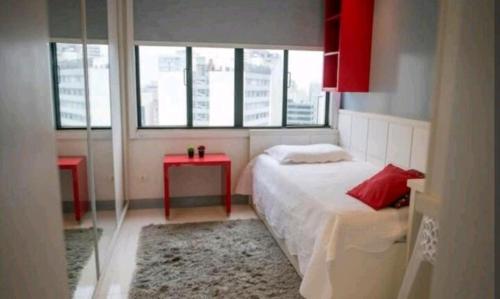 een slaapkamer met een bed en een rode tafel en ramen bij Apart Luxo no Centro com hidromassagem in Curitiba