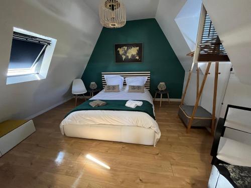 ein Schlafzimmer mit einem Bett mit einer grünen Wand in der Unterkunft Capcoz Les Glycines in Fouesnant