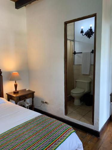 a bedroom with a bed and a toilet and a mirror at Villa de Antaño in Antigua Guatemala
