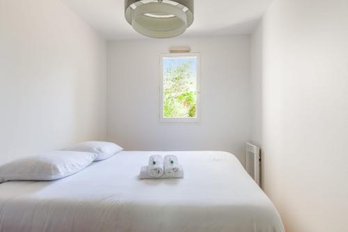 - une chambre dotée d'un lit blanc avec deux commandes dans l'établissement Appartement Charly - Welkeys, à Cabourg