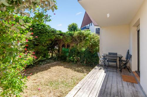 une terrasse en bois avec une table et des chaises. dans l'établissement Appartement Charly - Welkeys, à Cabourg