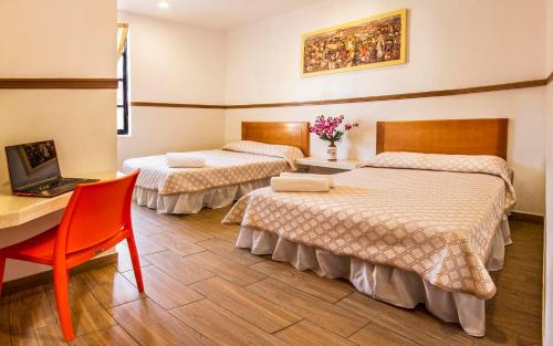 a room with two beds and a desk with a laptop at Hotel Templo Mayor in Mexico City