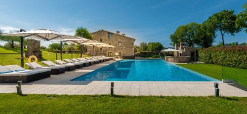 una piscina con tumbonas y sombrillas en Mas Rosset - Luxury Villa Girona - Costa Brava en Cornellá de Terri
