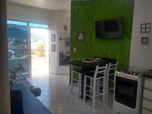 a living room with a green wall at APTO NA PRAIA DE 1 DORMITORIO COM VISTA PRO MAR a POUCOS PASSOS DA AREIA in Florianópolis