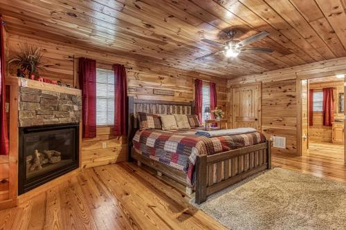 a log cabin bedroom with a bed and a fireplace at Always Kiss Me Goodnight-Hot Tub, Arcade, Near the Parkway! in Pigeon Forge