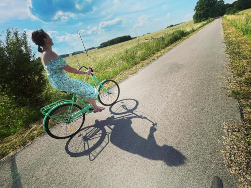 Una mujer con un vestido montando una bicicleta en un camino en Romantyczny domek dla dwojga en Jabłonka