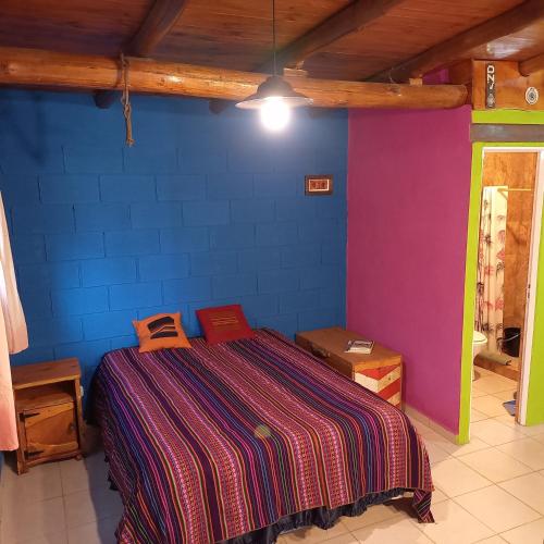 a bedroom with a bed with a purple and blue wall at Casita de Colores in Cosquín
