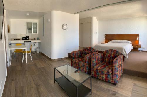 Dali Suites في تيخوانا: غرفه فندقيه بسرير واريكه وطاولة