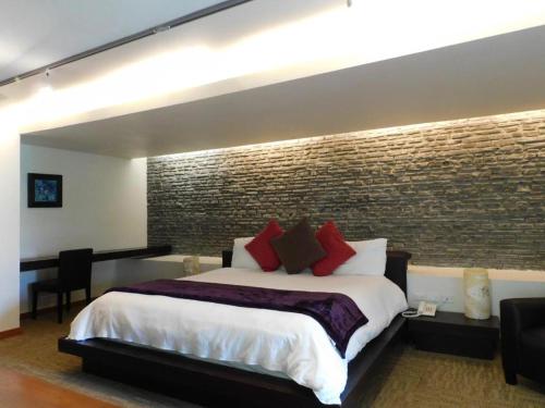 1 dormitorio con 1 cama grande y pared de ladrillo en Hotel & Spa Luna Canela Boutique, en Atlixco