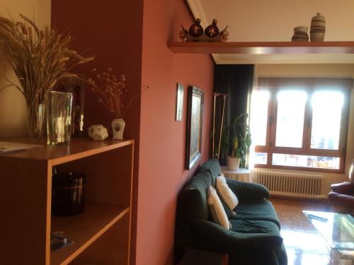 a living room with a green couch and a window at EL BALCÖN DE AVILÉS, acogedor con garaje en centro histórico, in Avilés