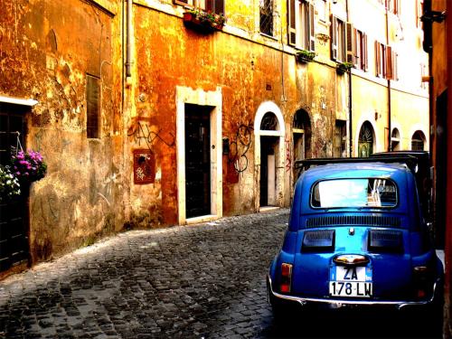a blue car parked on a street next to a building at Hotel Indigo Rome - St. George by IHG in Rome