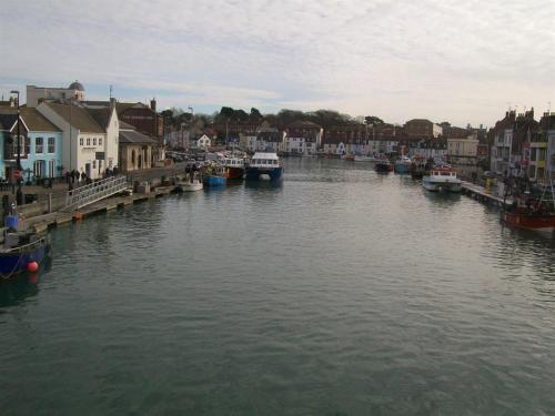 a river with boats in a town with houses at Boaters Guesthouse in Weymouth