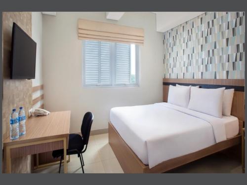 a bedroom with a bed and a desk with a computer at All Nite and Day Hotel Alam Sutera in Serpong