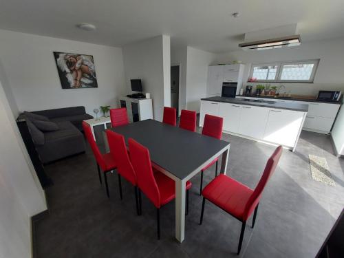 a kitchen and dining room with a table and red chairs at 2 modern private rooms with private Balcon fits for 5 persons in Vichten