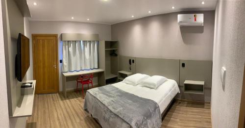 ein Hotelzimmer mit einem Bett und einem Schreibtisch in der Unterkunft Hotel Villa Inácia in Vacaria