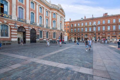 a group of people walking in front of a building at Very nice duplex located on the main square - Toulouse - Welkeys in Toulouse