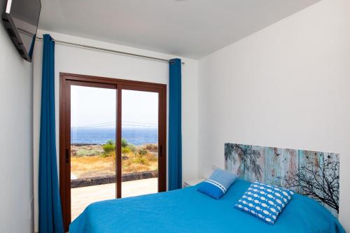 a bedroom with a blue bed and a view of the ocean at Casa Tabaiba Dulce in Frontera