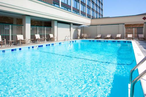 a swimming pool in a hotel with chairs and tables at Holiday Inn Express Washington DC SW - Springfield, an IHG Hotel in Springfield