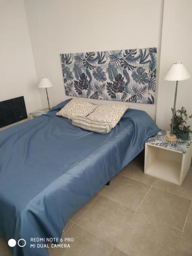 a bedroom with a bed with a blue comforter at Castex in Cordoba