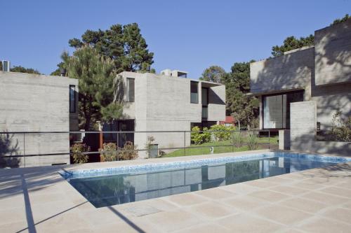 una casa con piscina frente a un edificio en V&D - Casas en Mar Azul en Balneario Mar Azul