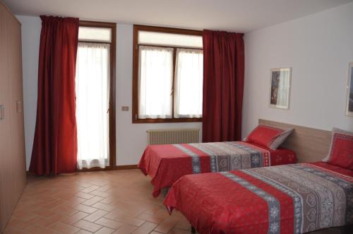 um quarto com 2 camas e janelas com cortinas vermelhas em Appartamento Giada Pozzale di Pieve di Cadore(BL) em Pieve di Cadore