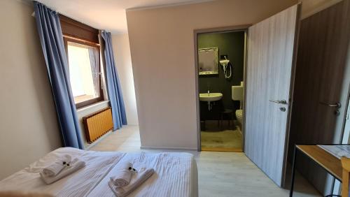 ein Schlafzimmer mit einem Bett und ein Badezimmer mit einem Waschbecken in der Unterkunft Pension Knafel in Žirovnica