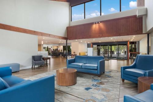a lobby with blue chairs and tables and windows at Best Western Hunt's Landing Hotel Matamoras Milford in Matamoras
