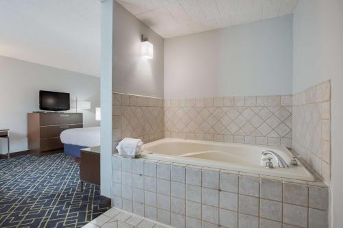 ein Hotelzimmer mit einer Badewanne und einem Bett in der Unterkunft Best Western Hunt's Landing Hotel Matamoras Milford in Matamoras