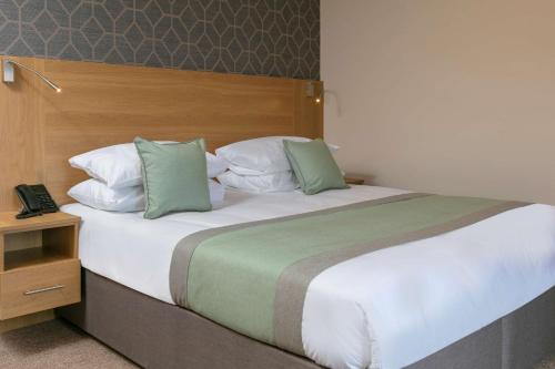 a bedroom with a large bed with green and white pillows at Best Western Northfields Ealing Hotel in London