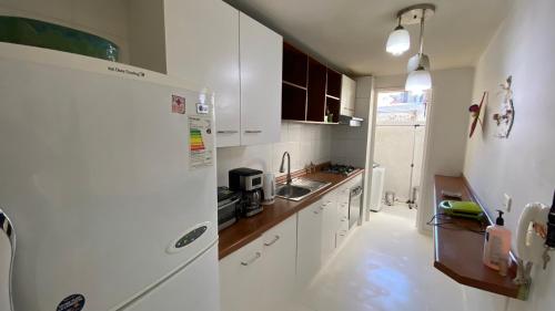 a white kitchen with a sink and a refrigerator at Jardines in Santiago