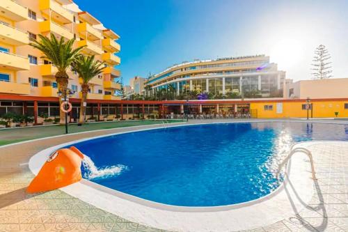 einem Pool mit Rutsche in einem Gebäude in der Unterkunft Luminoso y bonito apartamento con piscina en frente del mar in Los Cristianos