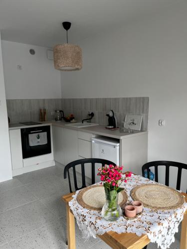a kitchen with a table with a vase of flowers on it at marga_apt in Świnoujście