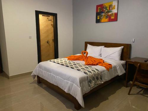 a bedroom with a bed with an orange robe on it at Odadi Guesthouse in Dalung