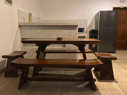 a wooden table and bench in a kitchen with a refrigerator at Odadi Guesthouse in Dalung