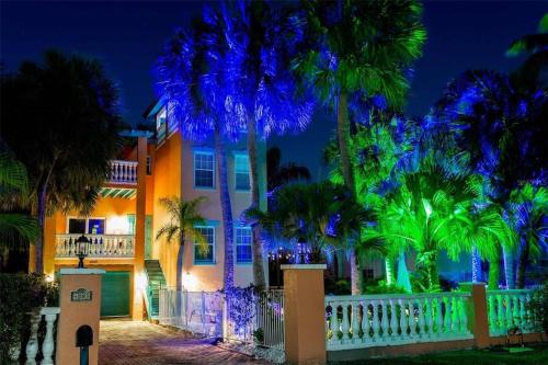 a house with a white fence and palm trees at night at Tropical luxury pool home by the beach with roof top lounge centrally located on Anna Maria Island in Holmes Beach