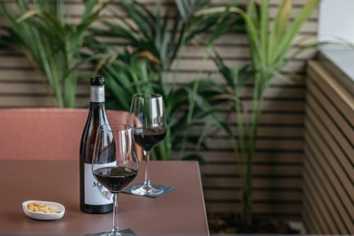 two wine glasses and a bottle of wine on a table at InterContinental Barcelona by IHG in Barcelona