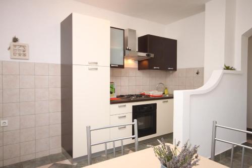 uma cozinha com armários brancos e um fogão em Apartments with a parking space Maslenica, Novigrad - 6548 em Jasenice