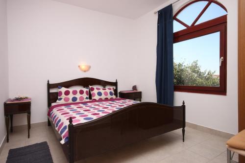 Schlafzimmer mit einem Bett mit rosa Kissen und einem Fenster in der Unterkunft Apartments with a parking space Maslenica, Novigrad - 6548 in Jasenice