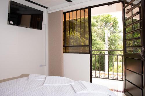 een slaapkamer met een bed en een groot raam bij RAKIRA SUITES APARTAHOTEL CAMPESTRE in Ráquira
