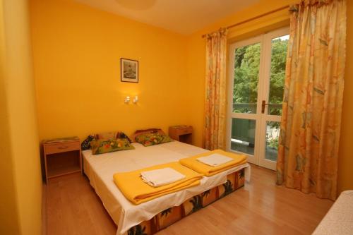 een slaapkamer met een bed met gele muren en een raam bij Apartments and rooms with parking space Podgora, Makarska - 6706 in Podgora