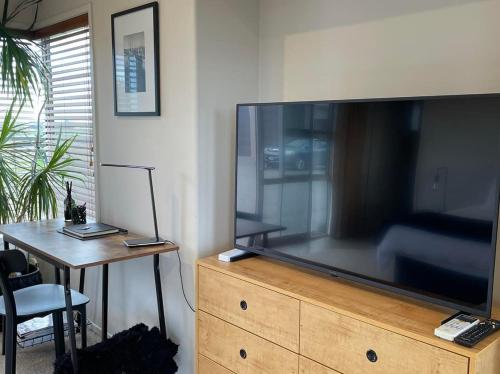 a large flat screen tv on a dresser with a table at Views to unwind - self contained unit w/king bed in Ruakaka