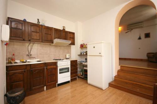 a kitchen with wooden cabinets and a white refrigerator at Apartments with a parking space Podgora, Makarska - 6645 in Podgora