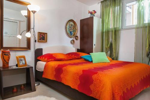 a bedroom with a bed with an orange blanket and a window at Apartments by the sea Makarska - 6843 in Makarska
