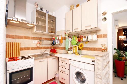 eine Küche mit weißen Schränken und einer Waschmaschine in der Unterkunft Apartments by the sea Makarska - 6843 in Makarska