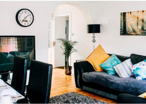 a living room with a couch and a clock on the wall at Home to Home Stay Apartment in Hogganfield