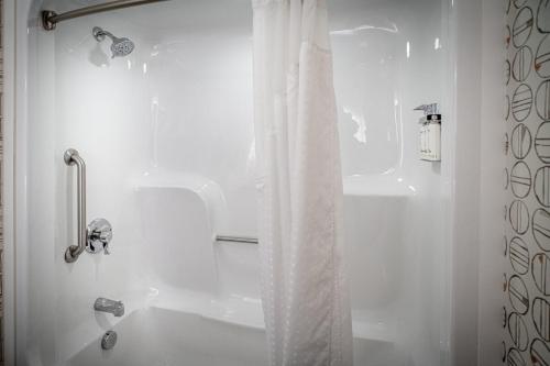 a bathroom with a shower with a white shower curtain at Holiday Inn Hotel & Suites Beckley by IHG in Beckley