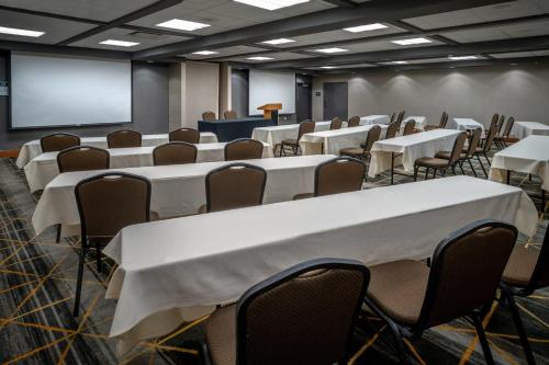 a conference room with tables and chairs and a screen at Holiday Inn Hotel & Suites Beckley by IHG in Beckley