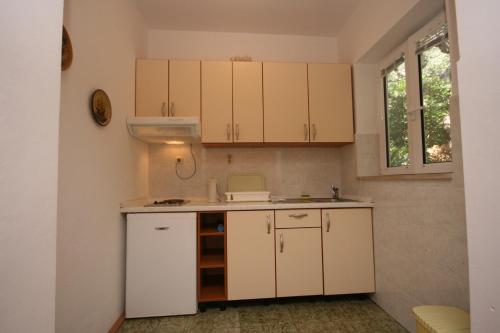 una cocina con armarios blancos y fregadero en Apartments by the sea Tucepi, Makarska - 6806 en Tučepi